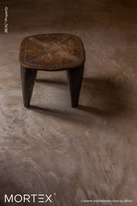 Mortex mineral skin floor finish in bronze tone with wooden stool